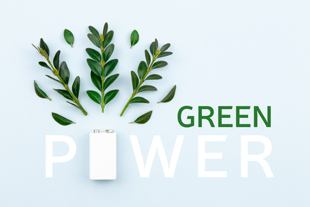 Eco energy or green power illustration with a white battery and sprigs leaves on a light background with copy space for textの写真素材