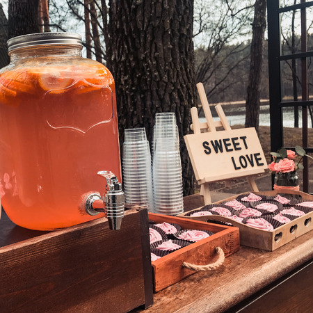 Location with summer drinks in glass jars or cupcake cans with a sign that says sweet loveの写真素材