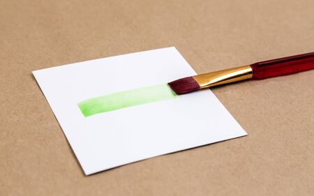 Paintbrush with smear of green paint. Smear of vivid green paint from brush on a piece of white paperの写真素材