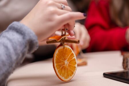 Women's hand making decorations from dried oranges, stars from tangerine and cinnamon. Girls party...