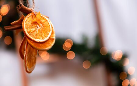 Hanging Christmas decoration of dried oranges, tangerine and cinnamon stars with copy space for text. holiday concept. blurred background.の写真素材