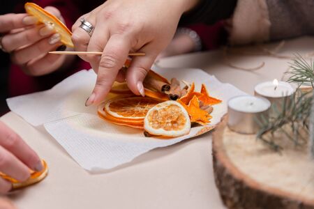 Women's hand making decorations from dried oranges, stars from tangerine and cinnamon. Girls party or meeting.の写真素材