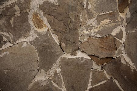 Fragment of a wall from a chipped stone. Wall stone background.