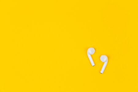 White earphones on yellow background with copy space.