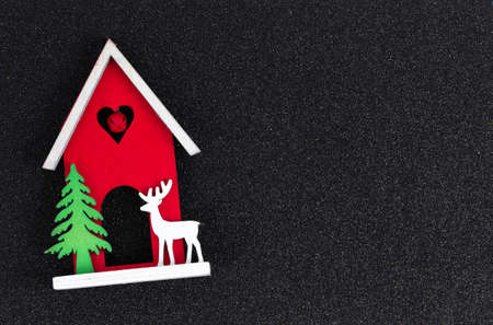 Christmas flatlay layout. wooden toy house, a deer and a Christmas tree on a black glitter shiny background. Christmas card with place for textの写真素材