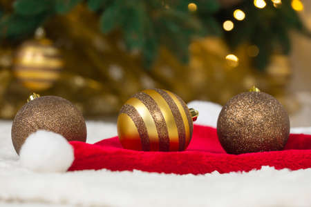 Christmas concept. Golden baubles on Santa Claus hat and Christmas treeの写真素材
