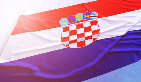 Croatia flag on the blue sky. Close up national flag in bright rays sun that is waving in the wind...