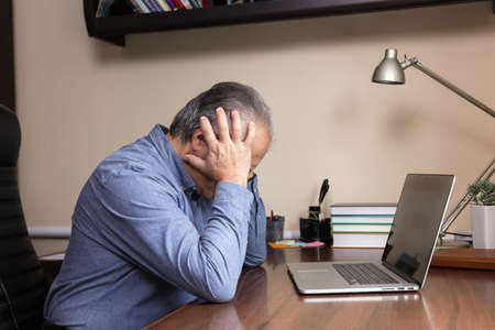 Senior man learn to use computer. Old man in glass and blue shirt using a laptop computer for online...