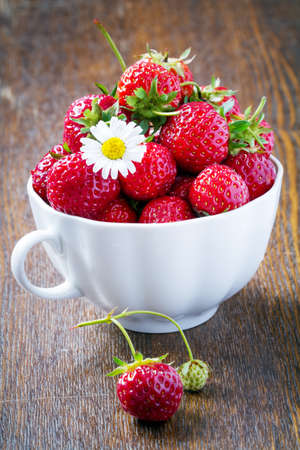 fresh strawberries in a white cup on a wooden backgroundの写真素材