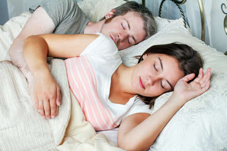 Young husband and wife sleeping on the bed in bedroomの写真素材