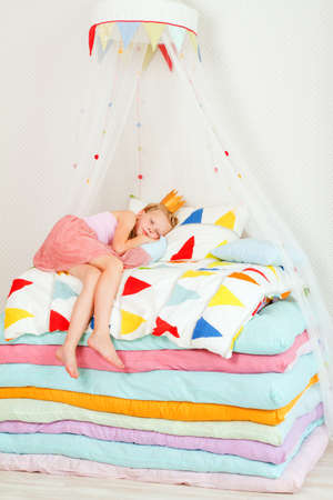 little girl lying on a pile of mattresses. the fairy tale "the princess on a pea"の写真素材