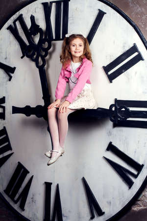 little girl sits on a huge clockwiseの写真素材