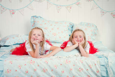 two cute little girls lying on the bedの写真素材