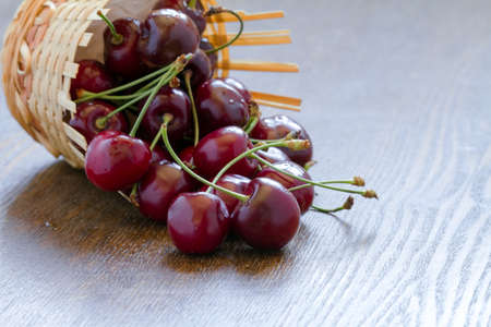 Fresh cherries in a basket on a wooden background