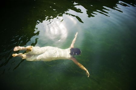 Young woman swimming under water in clear lakeの写真素材