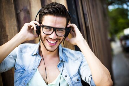 Young man listening music on the street - hipster style