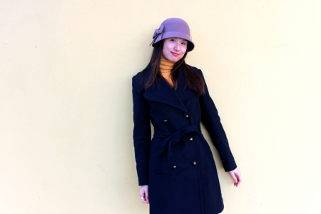 A girl in hat stand in front of wall, with shy expressionの写真素材