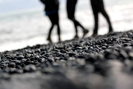 people walking behind the pebbles on the black beach in Vik, Icelandの写真素材