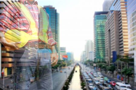 double exposure .engineer holding yeollw helmet in safety suit with blur cityscape  background,の写真素材
