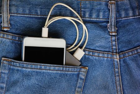 mobile phone with backup mobile battery in jean pocket.mobile phone is tranfer power from backup mobile battery.の写真素材