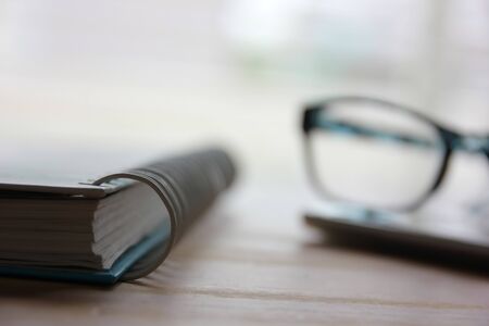 diary with spectales on smartphone in office