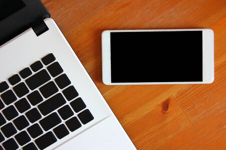top view of laptop with mobile phone on brown table ,copy space.の写真素材