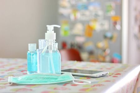 the alcohol in plastic bottle with mask ,mobile phone on tableの写真素材