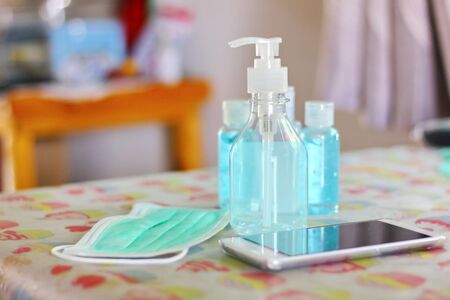 the alcohol in plastic bottle with mask ,mobile phone on tableの写真素材