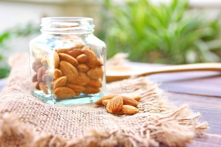 roasted organic brown almond seed  on sack floor  and  some of almond in the  square bottle.の写真素材