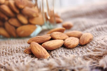 close up roasted organic brown almond seed  on sack floor  and  some of almond in the  square bottle.の写真素材