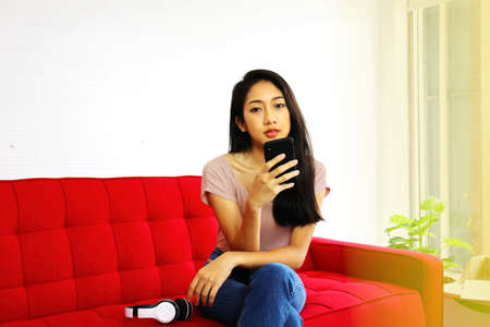 Asian young woman using mobile phone in living room in home