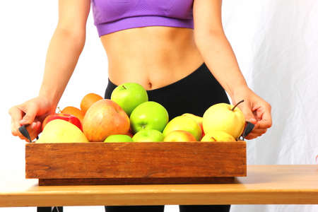 young woman in sport wear carry mix fresh fruit in wood container isolate on white backgroundの写真素材