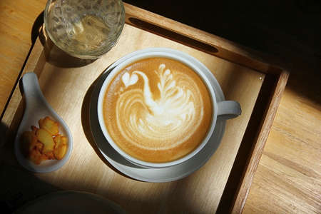 top view hot coffee in low key light .  hot  latte art surface design with low light the shade of tree.の写真素材