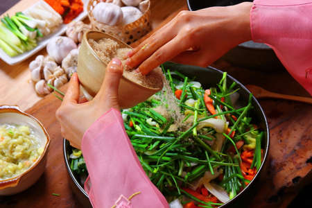top view Korean woman put sugar in to the bowl that many vegetables cooking kimchi  preserving vegetables to eat in winterの写真素材