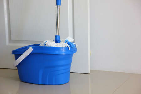 the new mop cleaning with blue plastic container in front of white doorの写真素材