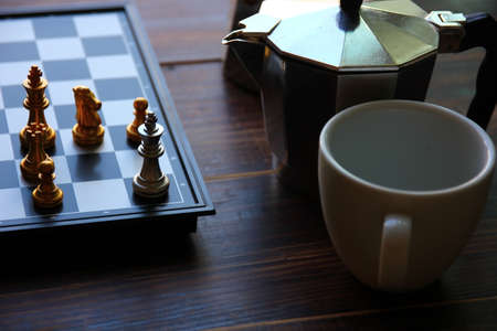 king chess in the corner of chess board on chess game with empty white ceramic coffee cupの写真素材