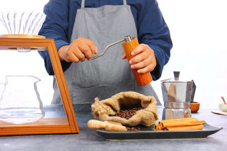 the barista using coffee grinder grined roasted coffee beans for drip coffee