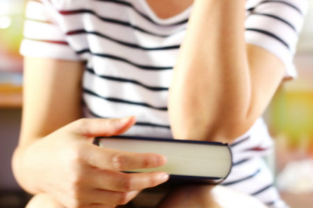 blur picture of woman holding book in hand and put on her elbow on book tooの写真素材