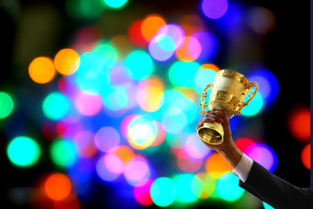 busines hand in suit holding the golden trophy  with multi color bokeh background, business conceptの写真素材