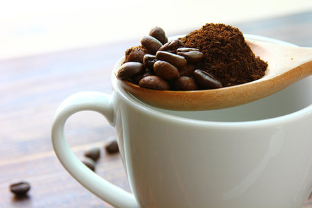 roasted coffee beans mix ground coffee on wooden spoon on white ceramic coffee cupの写真素材