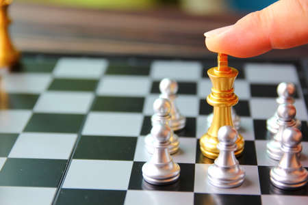 the finger on golden king chess between silver chess on chess boardの写真素材