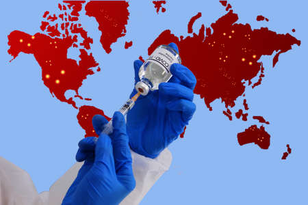 doctor in virus protective suit use syringes vacuuming vaccine start vaccination for people in out break country with  world map isolate on blue background.の写真素材