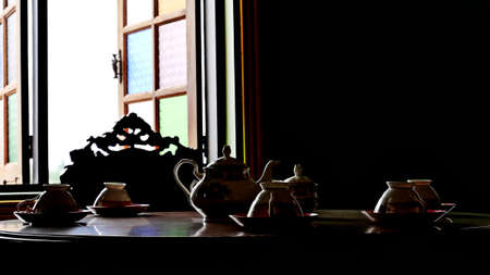 coffee or tea ceramic cup set vintage style on retro wood table under low lightの写真素材