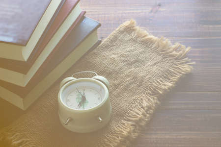 white alarm on sack with books stacking on retro floor. it is not late for learning , education...