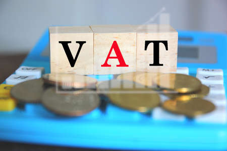 text VAT on wood cube on calculator and blur coins business graphの写真素材