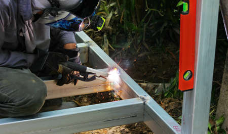 worker in safety uniform welding steel structure in construction site