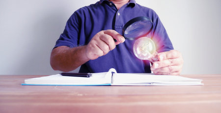 man holding light bulb in right hand with magnifying glass in left hand. man in posture using magnifying glass searching new idea , idea conceptの写真素材