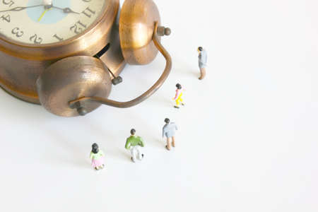 miniature people model looking the retro alarm clock isolate on whiteの写真素材
