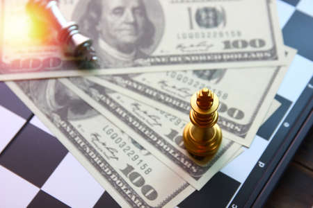 golden king chess set up on American dollar bank note while silver king chess lay down on chess board game , business conceptの写真素材