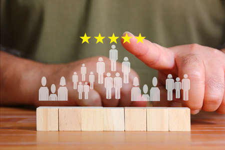 man used index finger touching yellow stars above illustration people icon on wood cube